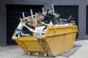 Yellow industrial skip full of disused office equipment